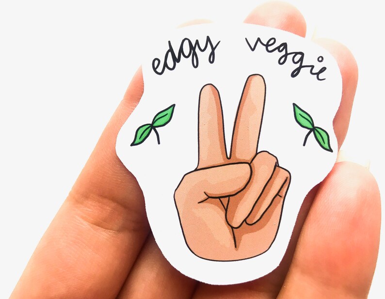 May include: White sticker with a peace sign hand gesture and the text "edgy veggie" in black cursive. Two green plant sprouts are on either side of the peace sign.