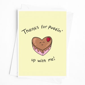 May include: A yellow card with the text "Thanks for puddin' up with me!" and a cartoon heart-shaped chocolate cake with a strawberry on top.
