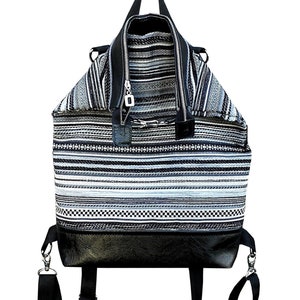 Könnte beinhalten: Ein schwarz-weiß gestreifter Rucksack mit schwarzen Lederelementen und verstellbaren Trägern.