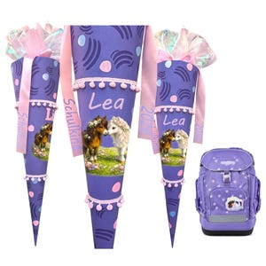 May include: Purple school cone and backpack set. The cone features a horse illustration, the name "Lea", and decorative patterns. The backpack is purple with white polka dots and a horse patch. Pink ribbons and trim add detail.