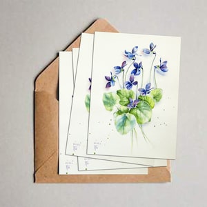 Cartão postal de flores violetas aquareladas. Nota de flores azuis em branco.