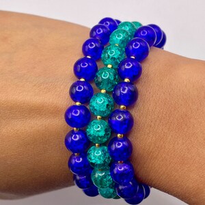 May include: A layered bracelet made of blue and teal glass beads with gold accents.
