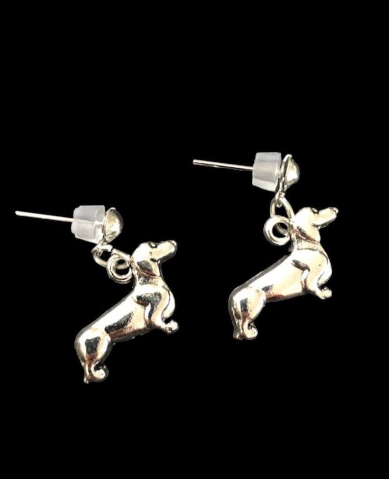Op de afbeelding: Een paar zilveren dackel oorbel studs. De oorbellen zijn klein en hebben een gedetailleerd dackel ontwerp.