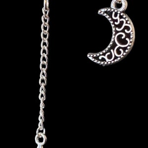 May include: A pair of silver earrings, one with a crescent moon charm and the other with a star charm hanging from a chain.