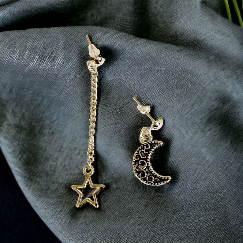 May include: A pair of silver earrings with a dangling star and a crescent moon charm. The earrings have a simple design and are perfect for everyday wear.