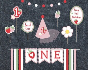 Puede incluir: Un conjunto de decoraciones para fiestas con temática de fresas, que incluye una pancarta con la palabra "ONE", un gorro de fiesta y varios letreros con las frases "Sweet One" y "Berry First Birthday". La combinación de colores incluye rosa, rojo y blanco.