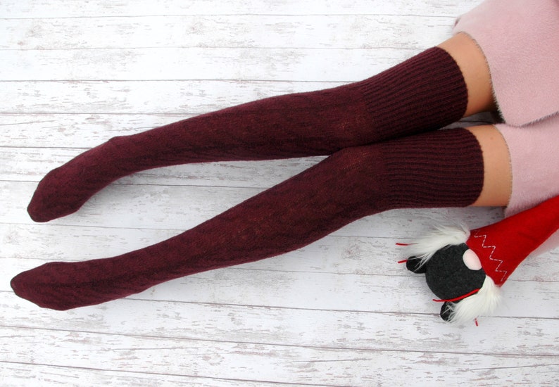 K&ouml;nnte beinhalten: Ein Paar burgunderfarbene Oberschenkelsocken mit gerippter Struktur. Die Socken sind aus einem weichen, warmen Material gefertigt und perfekt, um Ihre Beine im Winter warm zu halten.