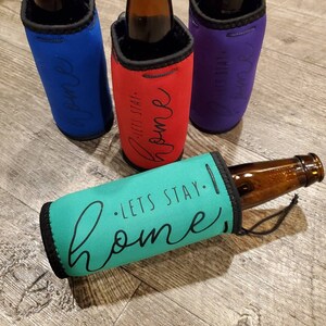 May include: Four insulated bottle coolers with different colored fabric and the text "Let's Stay Home" printed on them.