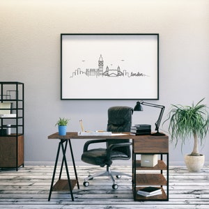 May include: A black framed picture of a line drawing of the London skyline, including Big Ben and Tower Bridge, with the word "london" written in cursive. The picture is hanging on a white wall above a wooden desk with a black office chair, a potted plant, and a desk lamp.