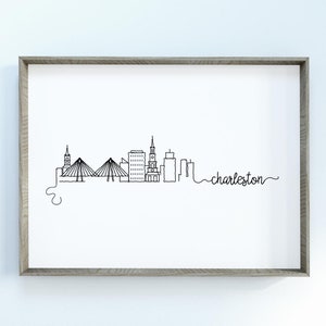 May include: A black and white line drawing of the Charleston, South Carolina skyline, including the iconic Ravenel Bridge and the city's historic churches. The text "charleston" is written in cursive below the skyline.