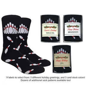 May include: Three gift boxes with black socks featuring a bowling pin pattern. Each box has a different holiday greeting label: "Season's Greetings", "Merry Christmas", and "Happy Holidays".