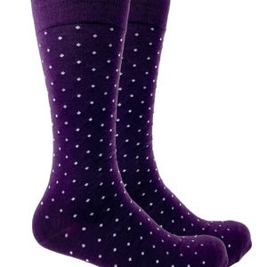 May include: A pair of knee-high socks in a deep purple hue, adorned with a repeating pattern of small white dots. The socks have a ribbed cuff and are made of a soft, likely knit, material. The socks are designed for comfort and style.