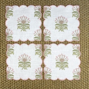 May include: Set of four pink and green floral embroidered linen napkins. The napkins have a scalloped edge and feature a delicate floral design.