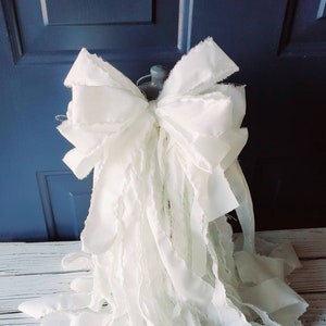 May include: A large white frayed ribbon bow, perfect for a Christmas tree topper or a decorative accent.