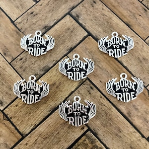 May include: Six silver charms with black lettering that reads "Born to Ride" with wings on either side.