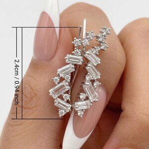 Puede incluir: Un pendiente de oreja plateado con un grupo de piedras transparentes, de corte rectangular y redondo. El pendiente mide 2,4 cm (0,94 pulgadas) de largo. Las piedras est&aacute;n dispuestas en cascada.