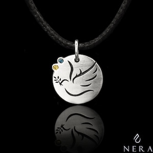 May include: Silver pendant necklace with a dove design and three small gemstones. The dove is holding an olive branch in its beak. The necklace is on a black cord.