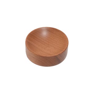 May include: A small, round wooden bowl with a smooth, light brown finish. The bowl is ideal for holding small items such as jewellery or keys.
