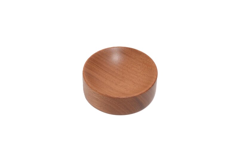 May include: A small, round wooden bowl with a smooth, light brown finish. The bowl is ideal for holding small items such as jewellery or keys.