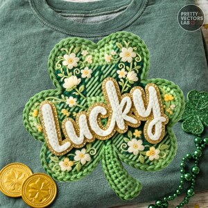 May include: Green sweatshirt with a large, embroidered shamrock design. The shamrock features white and yellow flowers, with the word "Lucky" in white and gold lettering. Two gold coins are visible near the shamrock, suggesting a St. Patrick's Day theme.