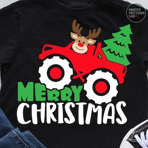 May include: A black t-shirt featuring a graphic of a red monster truck driven by a reindeer with a green Christmas tree in the back. The text "MERRY CHRISTMAS" is printed below in green and white. A logo for Pretty Vectors Lab is in the corner.