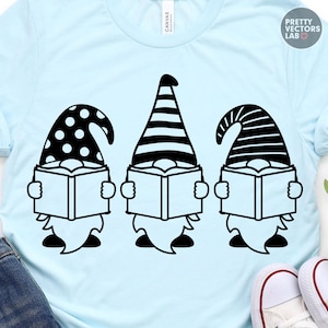 May include: A light blue t-shirt featuring a black graphic of three gnomes reading books. The first gnome wears a polka-dot hat, the second a striped hat, and the third a horizontally striped hat. The text Pretty Vectors Lab is in the corner.