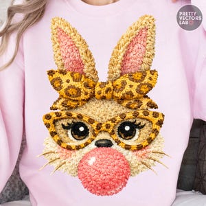 Puede incluir: Sudadera rosa claro con un diseño detallado de cara de conejo. El conejo tiene orejas grandes, un lazo y gafas con estampado de leopardo. Una burbuja de chicle rosa está frente a la cara del conejo. El texto "PRETTY VECTORS LAB" está en la esquina superior derecha.