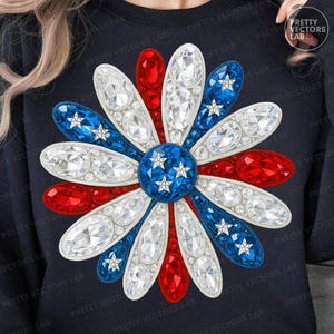 Pode incluir: Um moletom azul marinho com um grande design de flor brilhante. As pétalas da flor são vermelhas, brancas e azuis, com detalhes transparentes semelhantes a cristais e pequenas estrelas brancas, criando um tema patriótico.