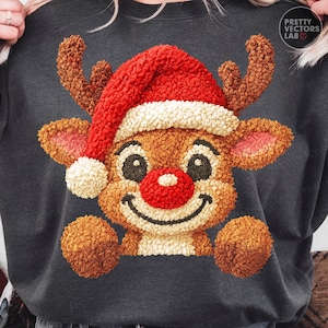 May include: Dark gray sweatshirt featuring a festive reindeer design. The reindeer has a red nose, a red Santa hat with white trim, and brown antlers. The reindeer's face is smiling, and the design has a textured, plush appearance. The sweatshirt is a cozy holiday-themed apparel.