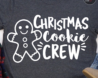 May include: A dark heather gray short-sleeve t-shirt featuring a white graphic of a gingerbread person and the text "CHRISTMAS Cookie CREW" in a mix of block and script fonts. The shirt has a round neckline and a small brand tag at the collar.