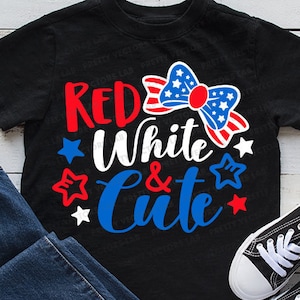 May include: A black t-shirt with the text "Red White & Cute" in red, white, and blue lettering. A red, white, and blue bow with stars is above the text.