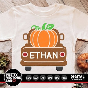 Op de afbeelding: Een bruine vrachtwagen met een pompoen in de laadbak en de naam "ETHAN" erop geschreven. De vrachtwagen staat op een wit T-shirt.