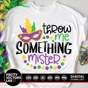 May include: A white t-shirt featuring a purple, green and gold Mardi Gras mask and the text "Throw me something mister" in black. The text is surrounded by green, purple and gold dots.