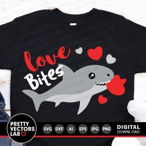 May include: A black t-shirt with a gray shark graphic biting a red heart. The text "love bites" is written in red and white letters above the shark. There are small white and red hearts scattered around the shark.