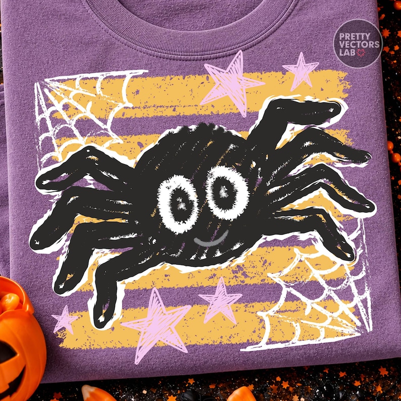 May include: A purple t-shirt featuring a graphic print of a black spider with large white eyes and a small smile. The design includes yellow horizontal stripes, white spider webs in the corners, and light pink stars. The text Pretty Vectors Lab is visible.