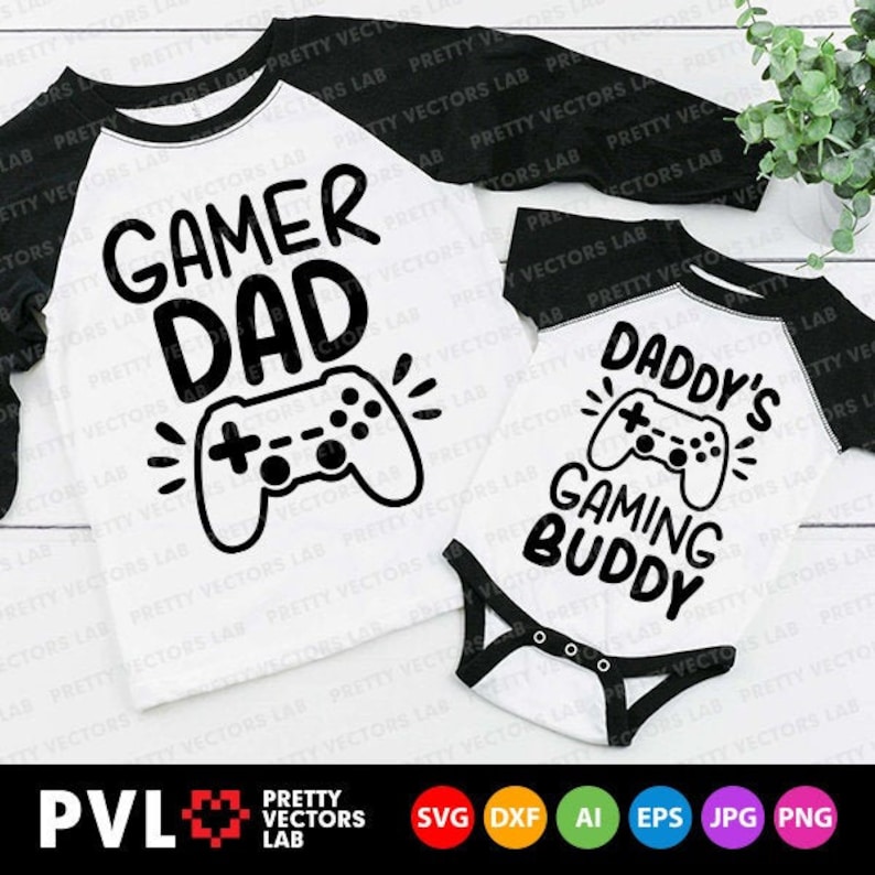 May include: Two white t-shirts with black sleeves and black text. The larger shirt says "Gamer Dad" with a video game controller graphic. The smaller shirt says "Daddy's Gaming Buddy" with a video game controller graphic.