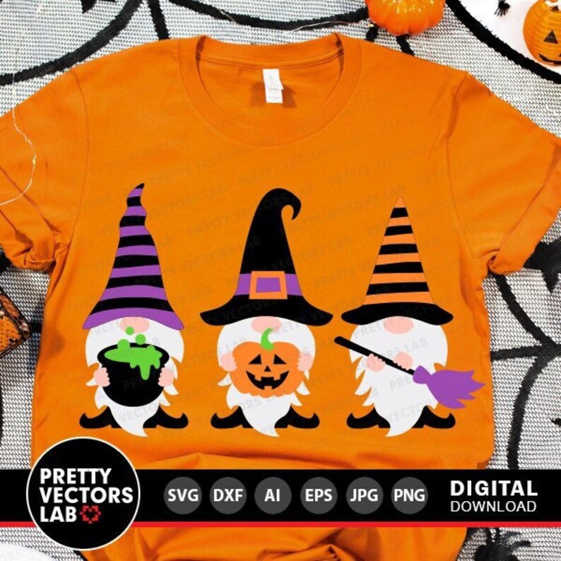 May include: Three Halloween gnomes wearing witch hats and holding a cauldron, a pumpkin, and a broom. The gnomes are on an orange t-shirt.