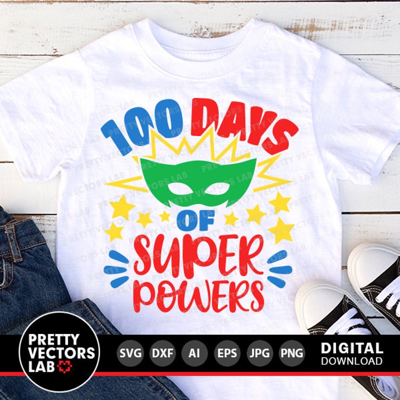 Pode incluir: Uma camiseta branca com um design gr&aacute;fico colorido que diz "100 dias de superpoderes". O gr&aacute;fico apresenta uma m&aacute;scara de super-her&oacute;i, estrelas e uma fonte em negrito.