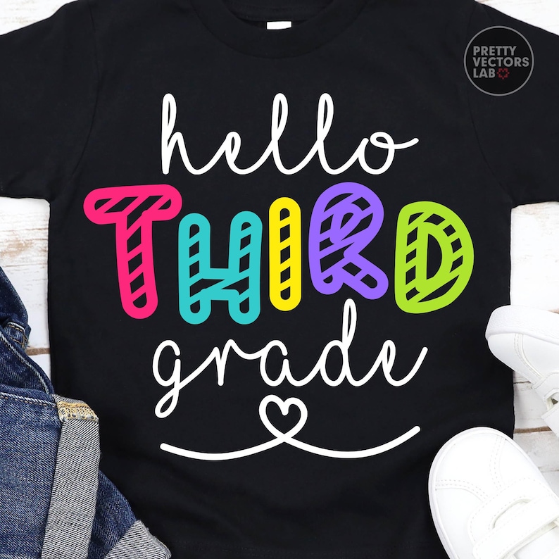 May include: A black short-sleeved t-shirt featuring the white cursive text hello, the colorful block letters THIRD in pink, teal, yellow, purple, and lime green, and the white cursive text grade with a heart icon underneath the lettering.