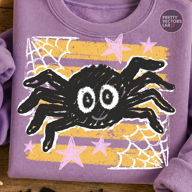 May include: A lavender sweatshirt featuring a central graphic of a black spider with large white eyes and a small smile. The design includes yellow horizontal stripes, white spiderwebs in the corners, and light pink stars. Text reads PRETTY VECTORS LAB.