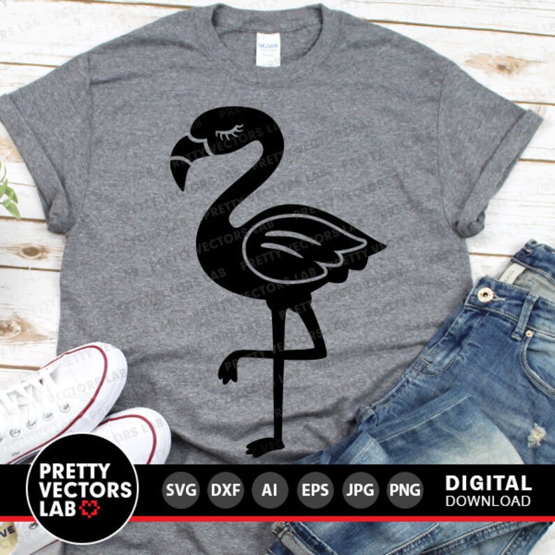 May include: A black silhouette of a flamingo with one leg raised, standing on a gray t-shirt. The t-shirt is laid out on a wooden surface with a pair of jeans and sneakers beside it. The text "PRETTY VECTORS LAB" is at the bottom of the image.
