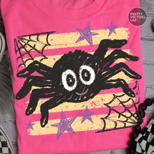 May include: A bright pink t-shirt featuring a central black spider graphic with large white eyes and a small smile. The design includes yellow horizontal distressed stripes, purple hand-drawn style stars, and black spiderwebs. Text reads PRETTY VECTORS LAB.