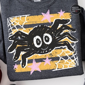 May include: A dark gray sweatshirt featuring a graphic print of a black spider with large white eyes and a small smile. The design includes yellow horizontal stripes, white spiderwebs in the corners, and pink stars. Text reads Pretty Vectors Lab.
