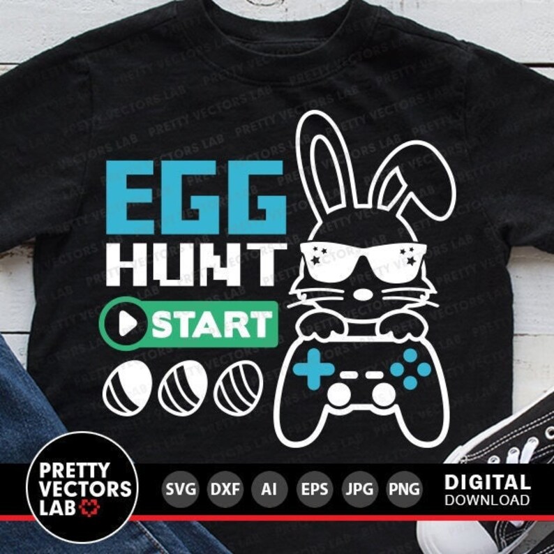 K&ouml;nnte beinhalten: Ein schwarzes T-Shirt mit einem wei&szlig;en Kaninchen, das eine Sonnenbrille tr&auml;gt und einen Videospielcontroller h&auml;lt. Der Text "EGG HUNT" befindet sich &uuml;ber dem Kaninchen und "START" unter dem Kaninchen. Unter dem Text "START" befinden sich drei wei&szlig;e Eier mit schwarzen Umrissen.