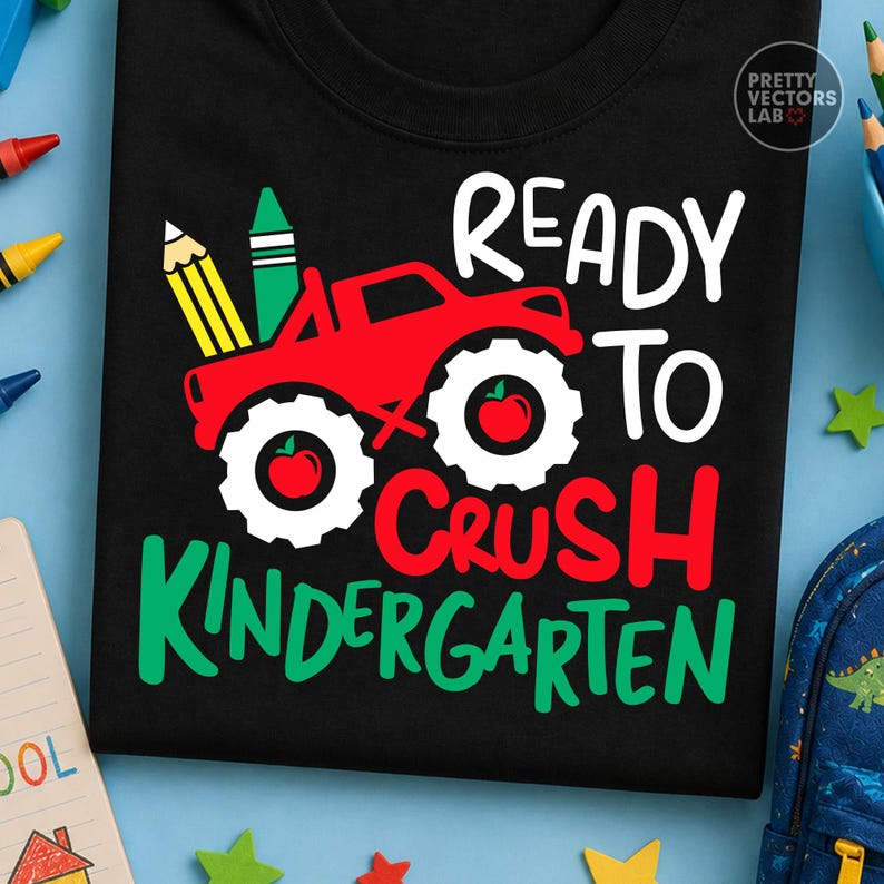 Puede incluir: Una camiseta negra con un gr&aacute;fico de un cami&oacute;n monstruo rojo con neum&aacute;ticos blancos, cada uno con una manzana roja. Sobre el cami&oacute;n hay un l&aacute;piz amarillo y un cray&oacute;n verde. El texto dice READY TO CRUSH KINDERGARTEN en letras blancas, rojas y verdes.