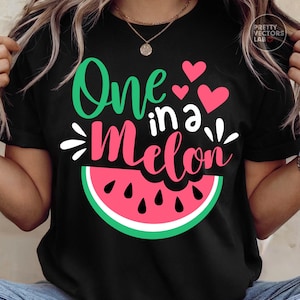 May include: A black short-sleeved t-shirt featuring a graphic of a watermelon slice and the text One in a Melon in green and pink script. The design includes three small pink hearts and white decorative accents above the watermelon slice.