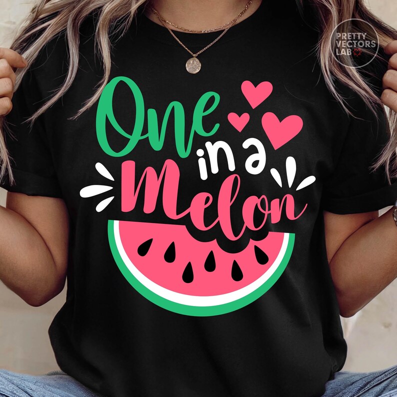 May include: A black short-sleeved t-shirt featuring a graphic of a watermelon slice and the text One in a Melon in green and pink script. The design includes three small pink hearts and white decorative accents above the watermelon slice.