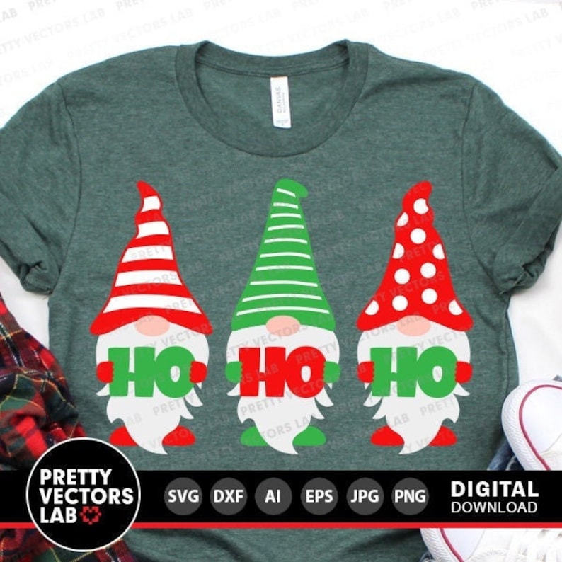 May include: Three gnomes holding the word "Ho Ho Ho" in green letters. The gnomes are wearing red and white striped hats, a green and white striped hat, and a red hat with white polka dots. The gnomes are on a green t-shirt.
