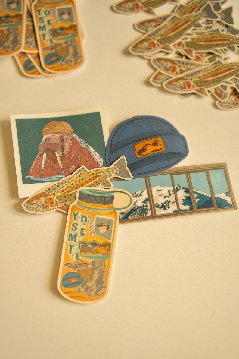 May include: A collection of stickers featuring a variety of designs, including a walrus wearing a hat, a fish, a mountain range, and a water bottle with the word "Yosemite" on it. The stickers are on a white background.