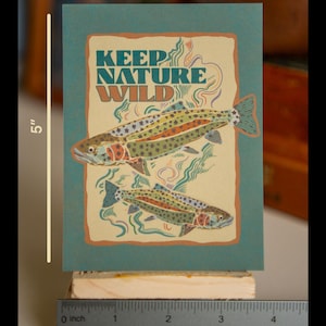 May include: A teal blue card with a tan border featuring two trout fish with black star patterns. The text "KEEP NATURE WILD" is in a retro font.